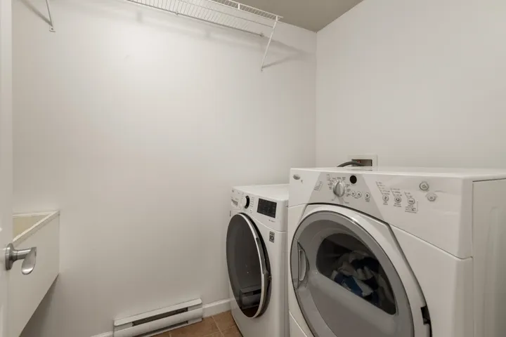 Laundry room featuring a baseboard heating unit, light tile patterned floors, and washer and clothes dryer