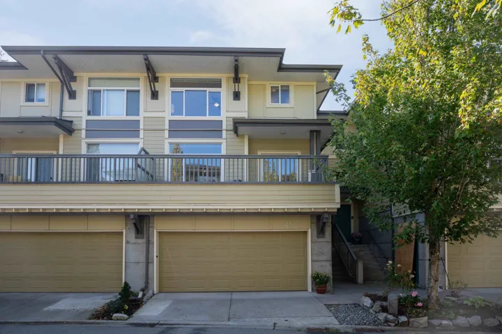 View of front of property with an attached garage, a balcony, and concrete driveway