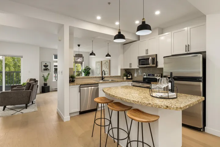 Kitchen featuring tasteful backsplash, stainless steel appliances, light stone countertops, hanging light fixtures, and white cabinets