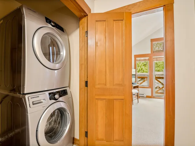 Washroom featuring vaulted ceiling, carpet, and estacked washer and dryer