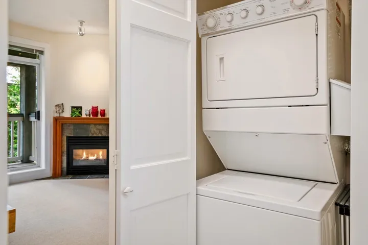 Laundry area featuring stacked washer and clothes dryer, a tile fireplace, and carpet