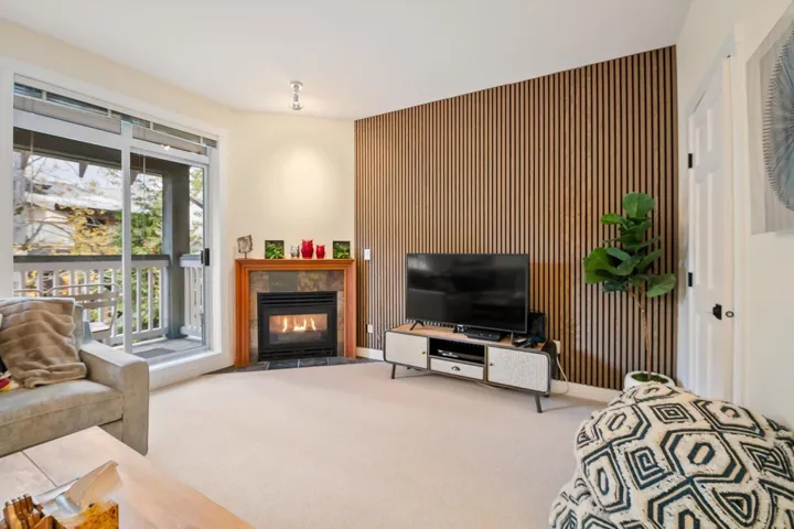 Carpeted living room with an accent wall, a fireplace, and wooden walls
