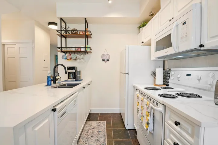 Kitchen with white appliances, a peninsula, and white cabinets