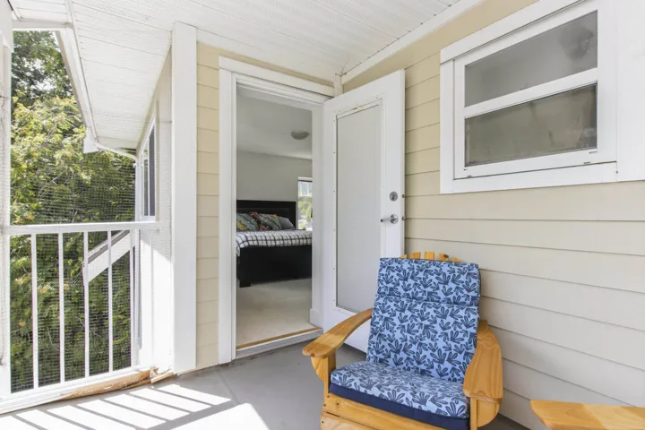 Screened balcony featuring exterior siding, a white railing, and a window with white trim
