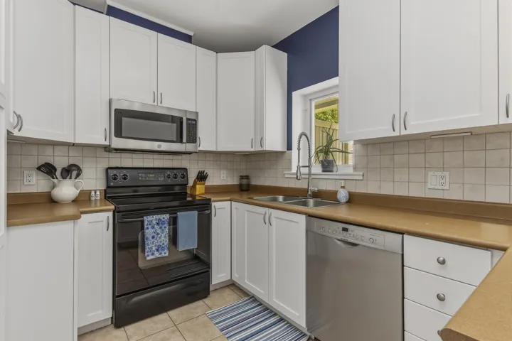 White cabinetry with silver hardware, an over-range microwave, and a black electric range