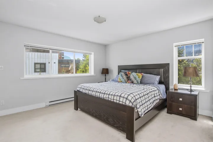 Bedroom featuring light gray walls, carpet flooring, baseboard heating, a large horizontal window, and an additional vertical window