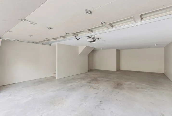 Spacious garage featuring a concrete floor, painted walls, overhead lighting, and an automatic garage door opener