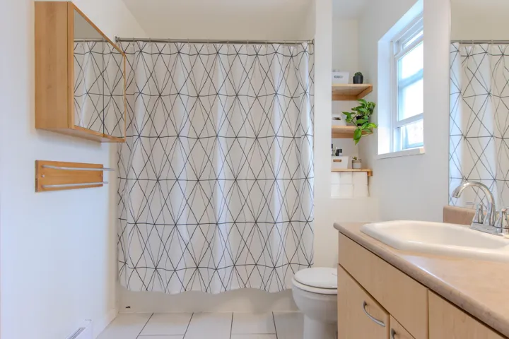 Full bathroom featuring vanity, light tile patterned floors, and curtained shower
