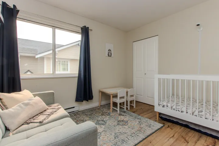 Bedroom featuring hardwood / wood-style floors, a nursery area, a baseboard radiator, and a closet