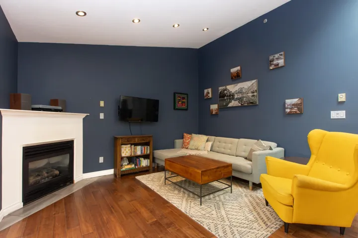 Living room featuring wood finished floors, a glass covered fireplace, and recessed lighting