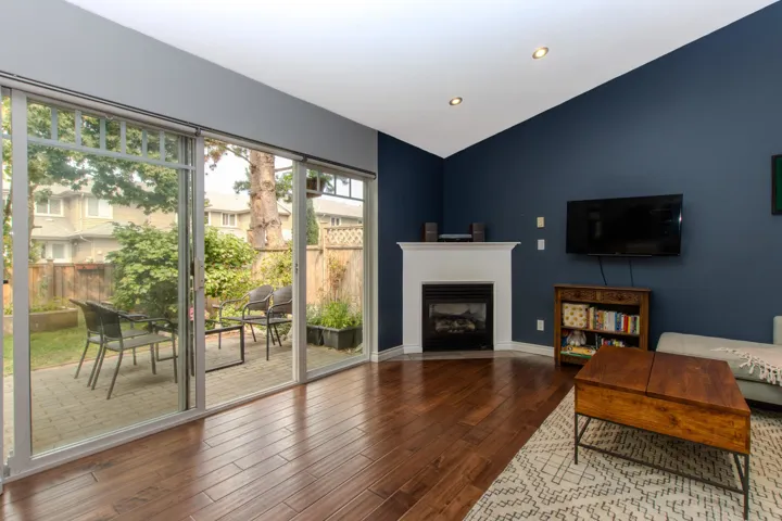 Living room featuring lofted ceiling, a fireplace with flush hearth, dark wood-type flooring, and recessed lighting