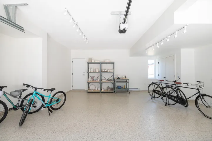 Spacious garage featuring a durable epoxy floor coating, track lighting, and a garage door opener