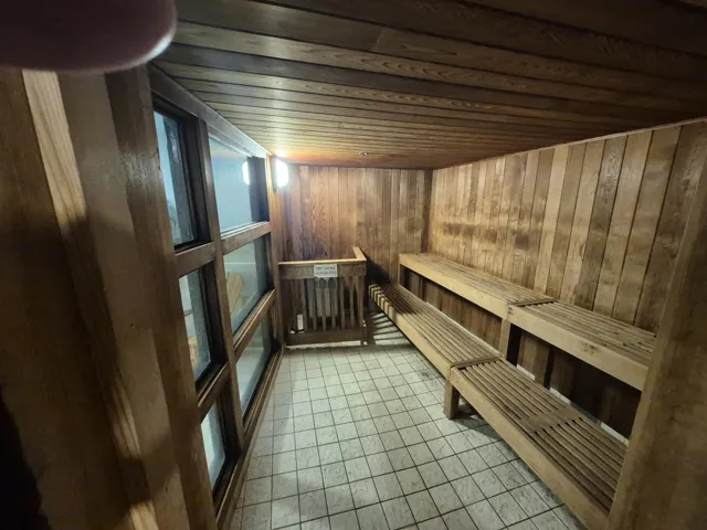 Sauna with wooden ceiling, wooden walls, and tile patterned floors