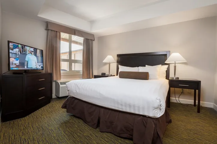 Bedroom featuring dark colored carpet, a wall mounted air conditioner, baseboards, and a raised ceiling