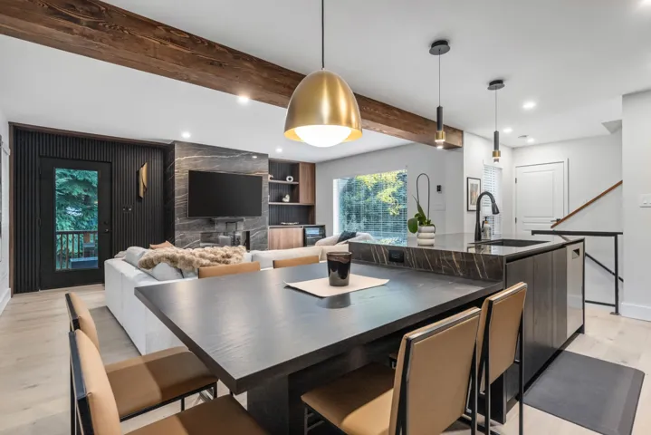 Kitchen featuring beamed ceiling, light wood-type flooring, hanging light fixtures, recessed lighting, and a center island with sink