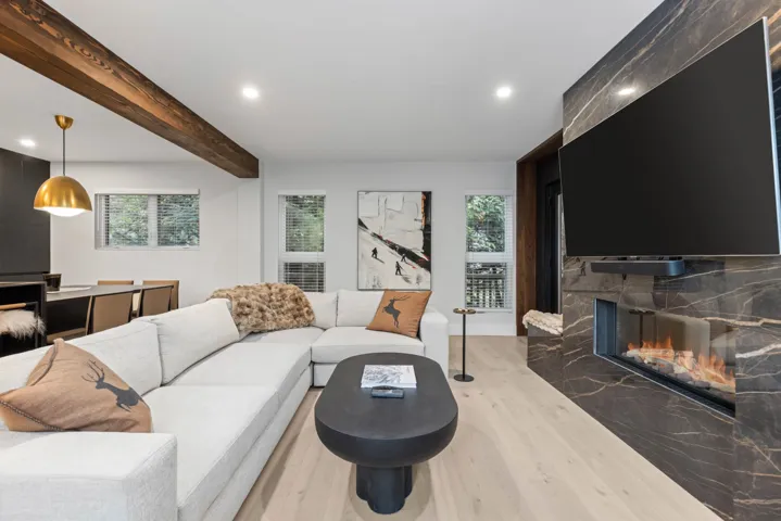 Living room with wood finished floors, beam ceiling, recessed lighting, and a fireplace