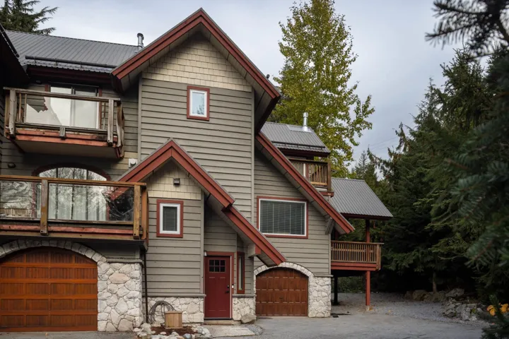 View of front of home featuring a metal roof, a garage, stone siding, and a balcony