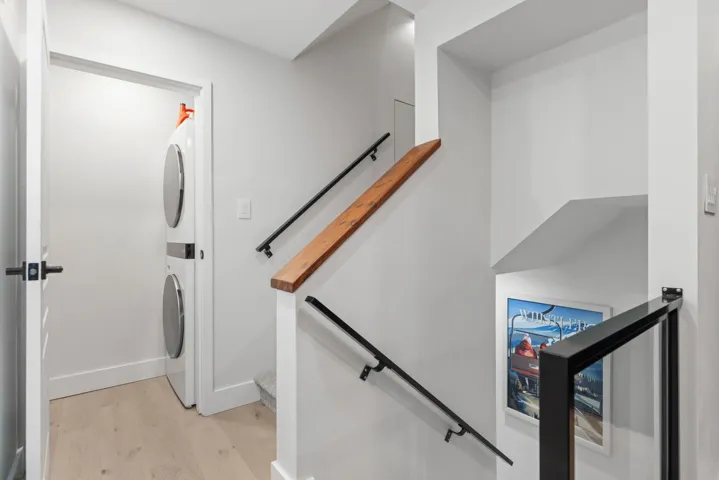 Staircase featuring wood finished floors and stacked washer and clothes dryer