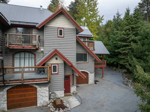 Chalet / cabin featuring a metal roof, a balcony, stone siding, and a garage