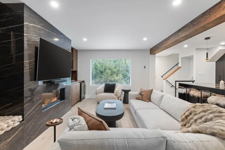 Living area featuring recessed lighting, a fireplace, beamed ceiling, and light wood-style floors