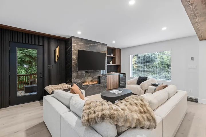 Living area featuring light wood-style floors, recessed lighting, beverage cooler, and a premium fireplace
