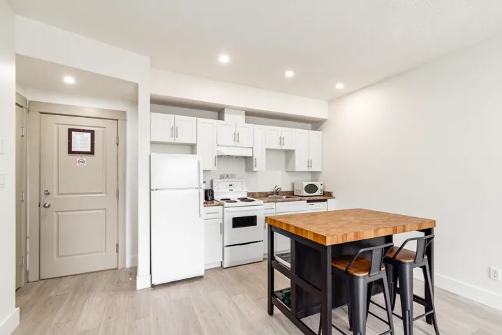 Compact kitchen area featuring white cabinetry, a wood-finish countertop, and stainless steel appliances