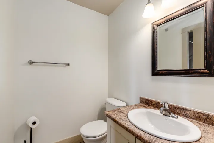 Bathroom vanity with an integrated oval sink, stone-finish countertop, and a wood-framed mirror