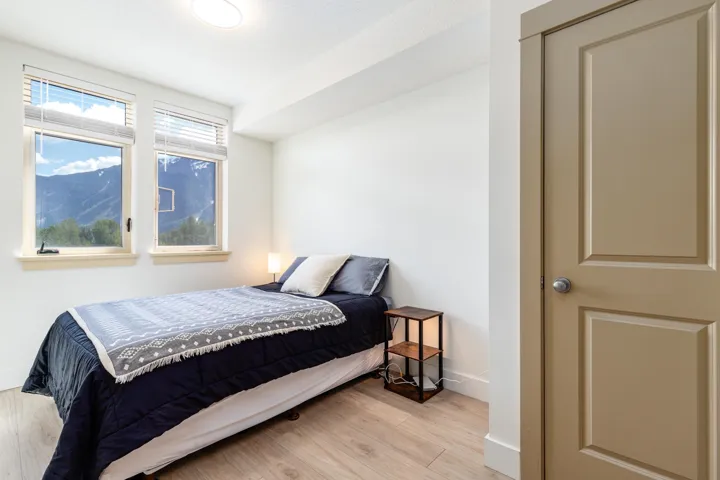 Bright room featuring two large windows, wood-finish flooring, and a contemporary flat-panel door