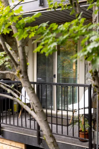 Private balcony featuring a sliding glass door, black metal railings, and stone-accented exterior walls