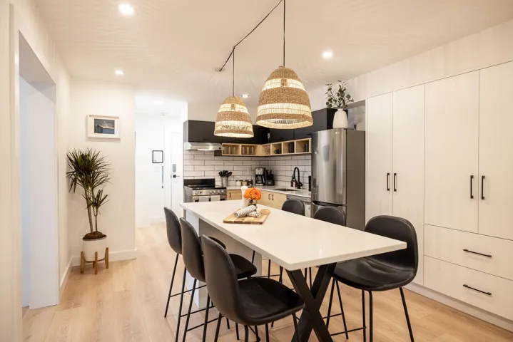 Open-concept kitchen featuring a large island with seating, a stainless steel refrigerator, and light wood-finish flooring