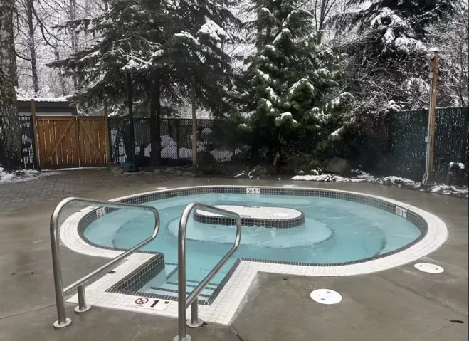 Outdoor spa with tiered seating, featuring a dark tile interior and white coping