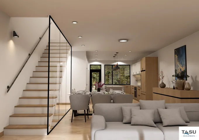 Open concept living space featuring a contemporary staircase with glass railing and black handrail, recessed lighting, wood-finish flooring, and a kitchen with light wood cabinetry and black-framed windows