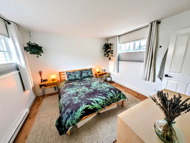 Bedroom featuring baseboards, wood finished floors, and a baseboard heating unit