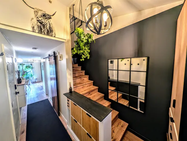 Stairs featuring a notable chandelier, baseboards, a barn door, and wood finished floors