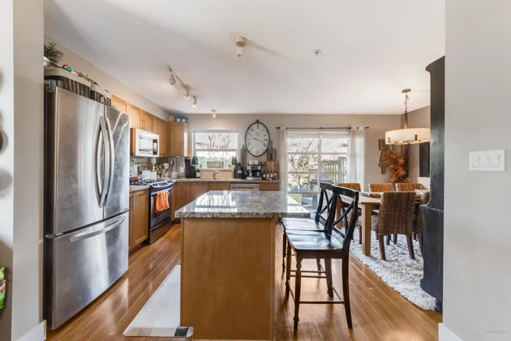 Kitchen featuring tasteful backsplash, a center island, a kitchen bar, wood finished floors, and stainless steel appliances