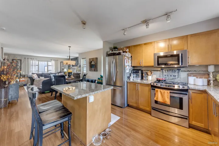 Kitchen featuring light wood-type flooring, a center island, backsplash, a kitchen bar, and stainless steel appliances