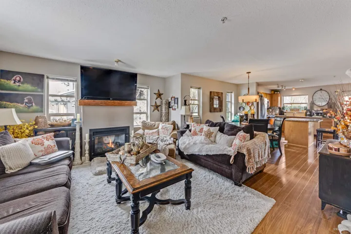 Living area with a large fireplace, light wood-style flooring, and a textured ceiling