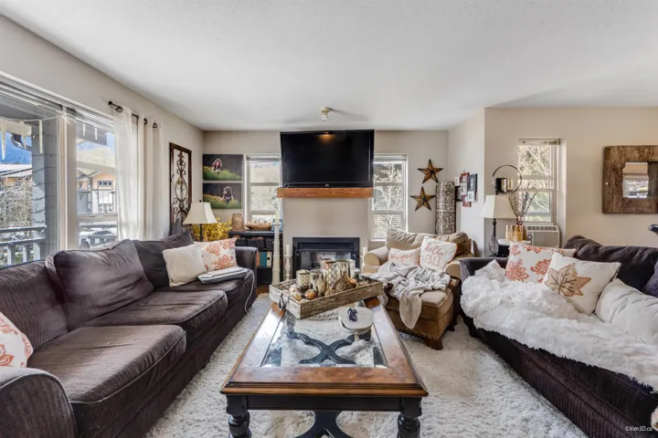 Carpeted living room featuring a glass covered fireplace and a textured ceiling