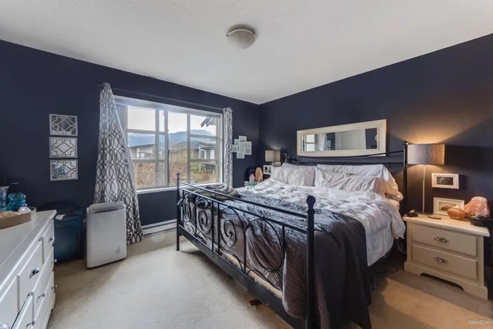 Bedroom featuring light carpet, a baseboard radiator, and a textured ceiling