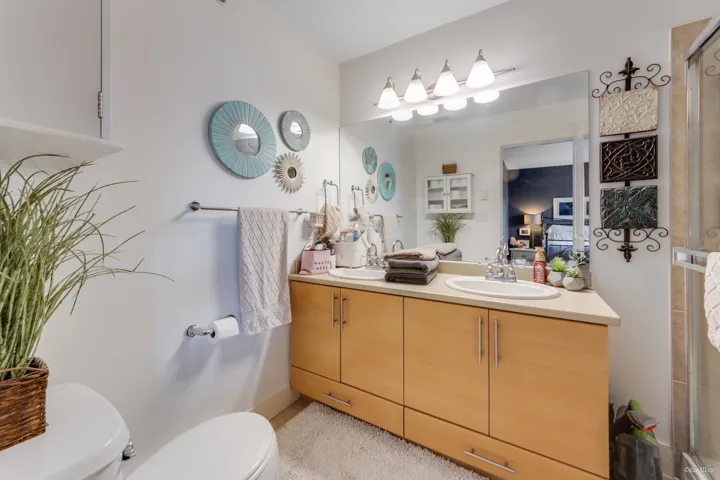 Ensuite bathroom featuring toilet, double vanity, a sink, and a shower stall