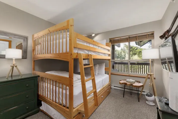 Bedroom with a baseboard heating unit and light colored carpet