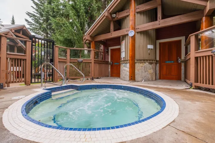 View of swimming pool featuring a hot tub, a patio area, and a gate