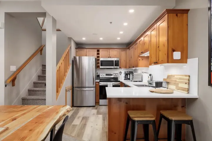 Kitchen with appliances with stainless steel finishes, a kitchen breakfast bar, light wood-style flooring, recessed lighting, and open shelves