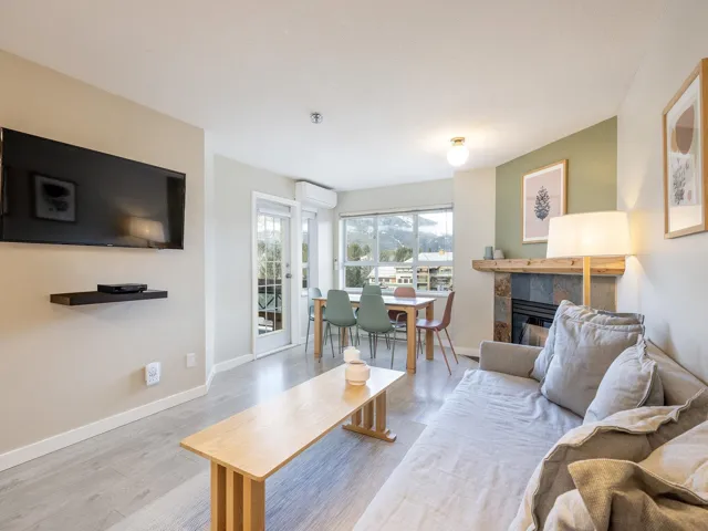 Living room featuring a tile fireplace, light wood-style floors, and a wall mounted AC