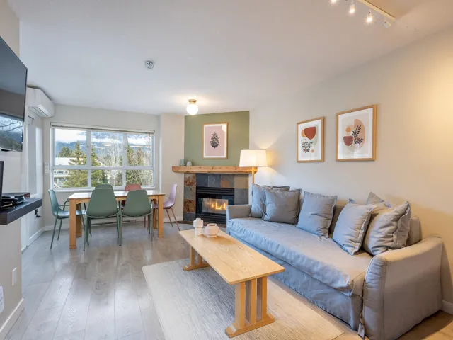 Living room featuring a tile fireplace, light wood-style flooring, and an AC wall unit