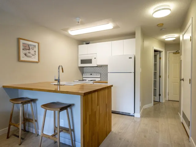 Kitchen with white appliances, a peninsula, white cabinets, tasteful backsplash, and a kitchen bar