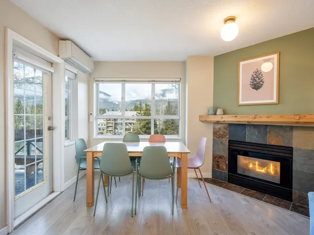 Dining area with a tiled fireplace, wood-type flooring, an AC wall unit, and a textured ceiling