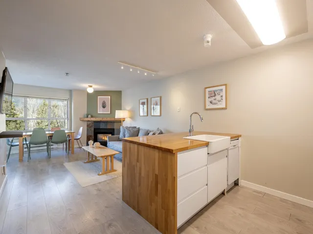 Kitchen with white cabinets, a tile fireplace, light wood-style flooring, wood counters, and a peninsula