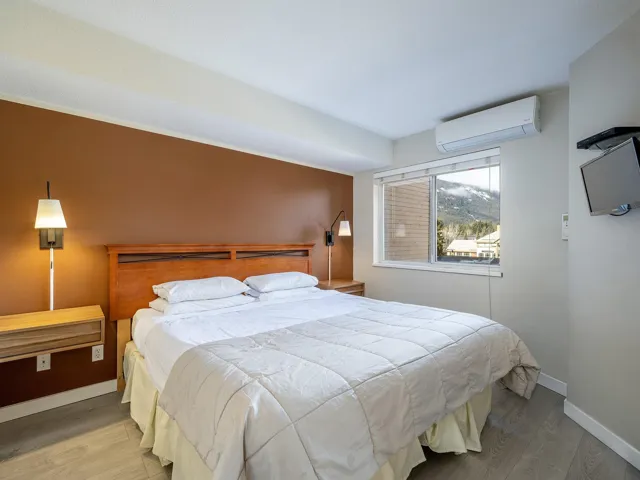 Bedroom with an AC wall unit and wood finished floors