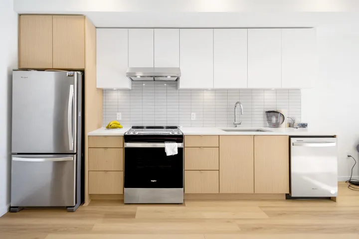 Two tone kitchen with stainless steel appliances, two tone cabinetry, modern cabinets, and light wood-style flooring